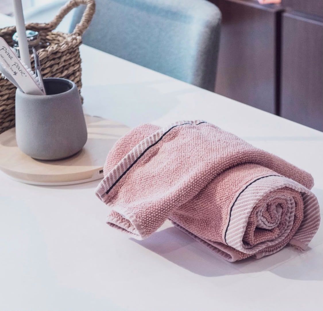 Linge de soin rose poudré roulé sur le plan de travail de l'institut